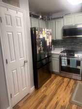 Kitchen featuring stainless steel appliances, dark wood-style floors, gray cabinets, and tasteful backsplash