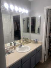 Bathroom with a walk in closet and vanity