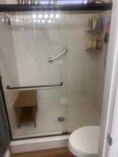 Full bathroom featuring a marble finish shower and wood finished floors