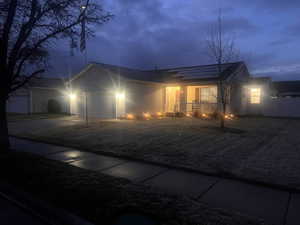 Ranch-style home featuring a garage, driveway, a gate, and solar panels