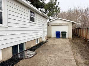 View of home's exterior featuring concrete driveway, a detached garage, and an outbuilding