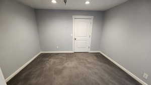 Empty room with dark colored carpet and recessed lighting