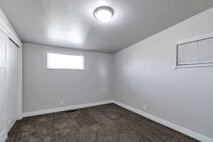 Unfurnished bedroom featuring a closet, dark colored carpet, and vaulted ceiling