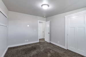 Unfurnished bedroom with dark colored carpet and a closet