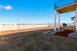 Fenced backyard featuring a mountain view and a balcony