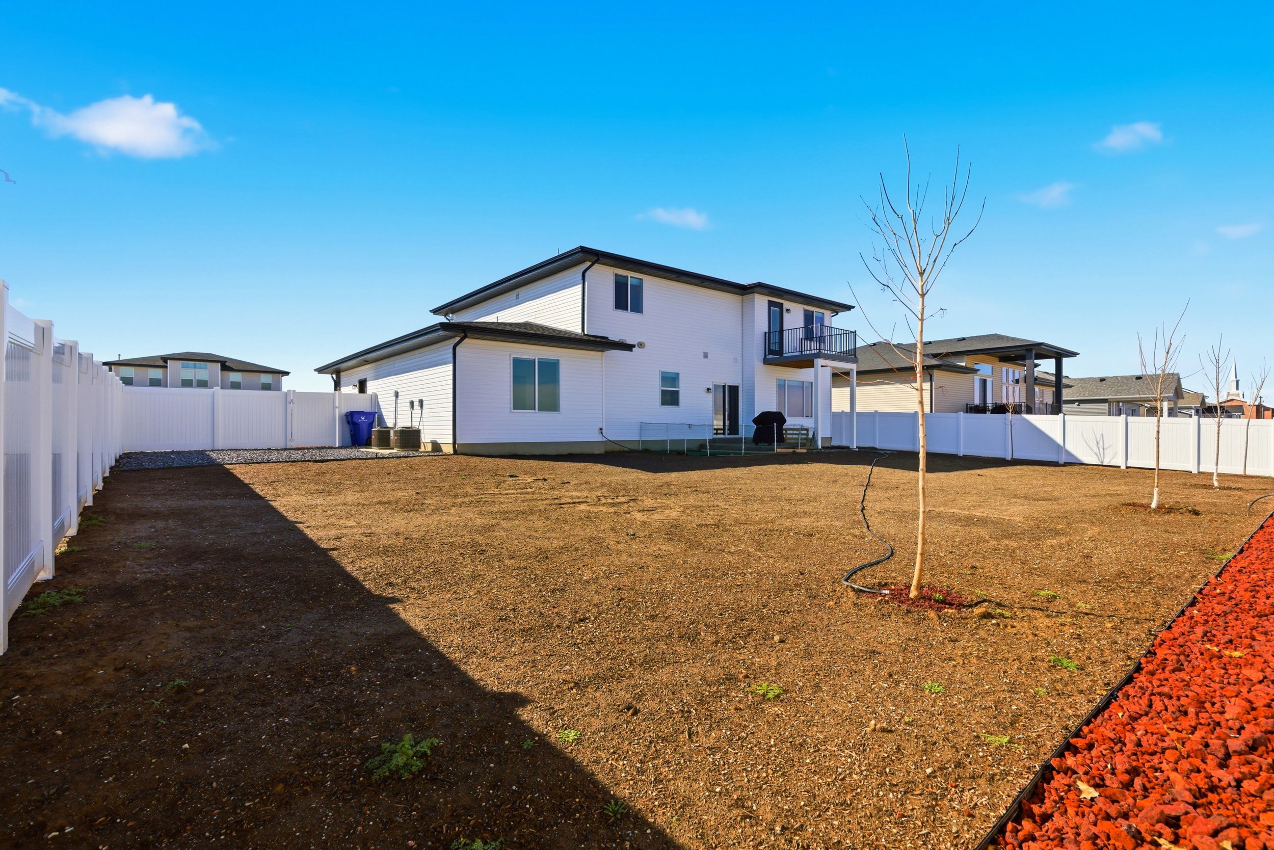 Back of property with a fenced backyard and a balcony