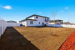 Back of property with a fenced backyard and a balcony