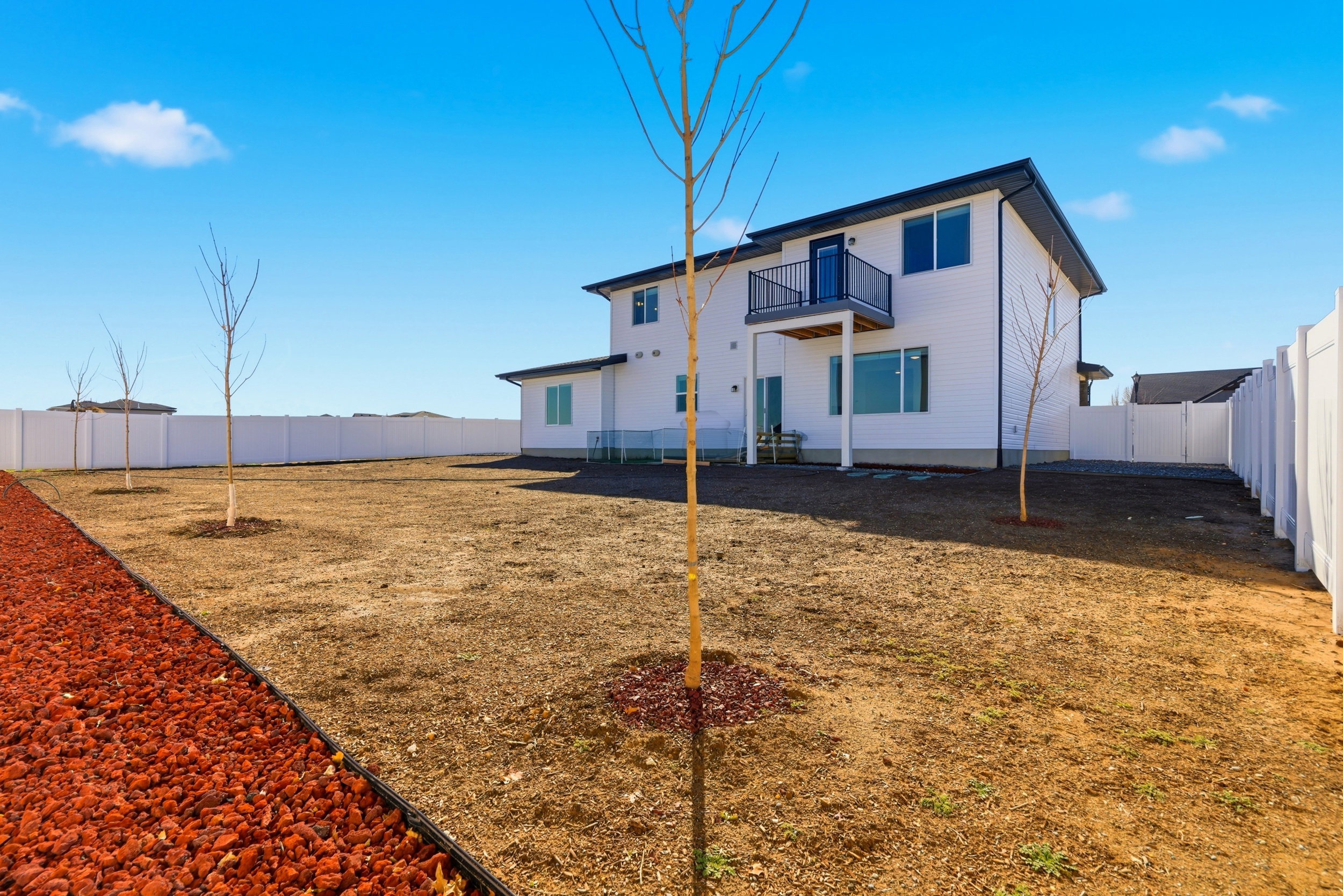 Back of house with a fenced backyard and a balcony