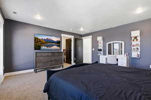 Carpeted bedroom featuring baseboards and an office area