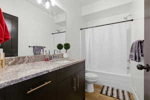 Full bath with vanity, light wood-style flooring, and shower / bathtub combination with curtain