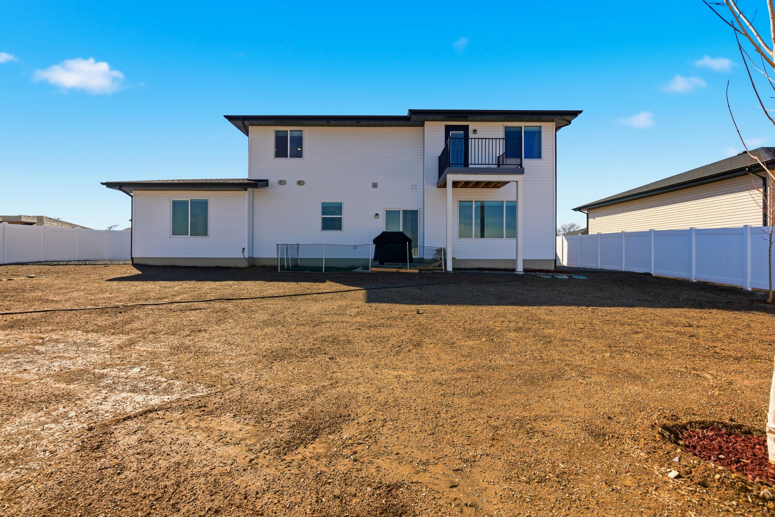 Back of property with a balcony, a fenced backyard, and a patio area