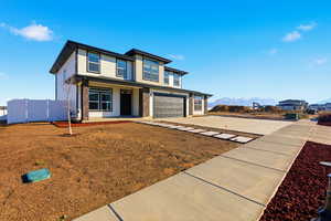 View of front of house with an attached garage, driveway, a mountain view, and a porch