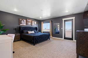 Bedroom with light carpet, access to exterior, and a textured ceiling