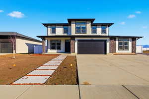 Prairie-style house featuring a porch, concrete driveway, a garage, and stone siding
