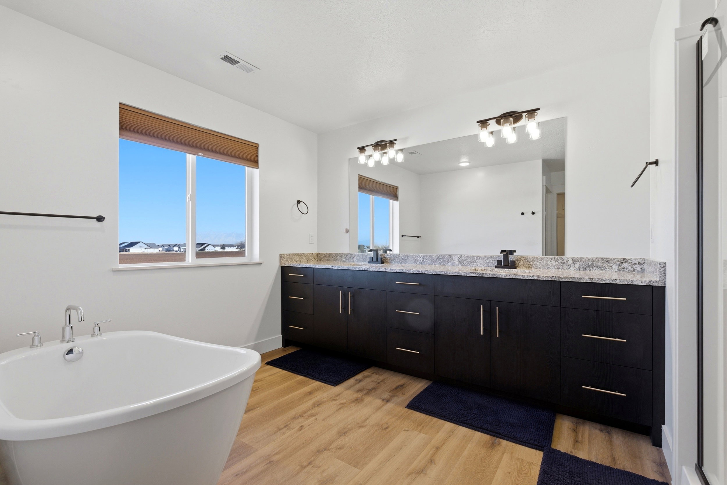 Full bathroom featuring double vanity, light wood-type flooring, and a freestanding bath