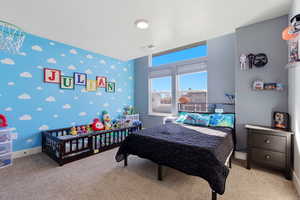 Bedroom with an accent wall, carpet flooring, and wallpapered walls