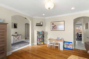 Game room featuring arched walkways, wood finished floors, ornamental molding, and recessed lighting