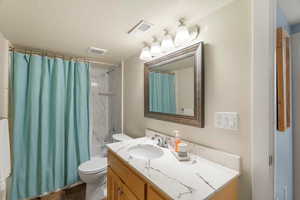 Full bathroom with vanity, shower / tub combo, and a textured ceiling