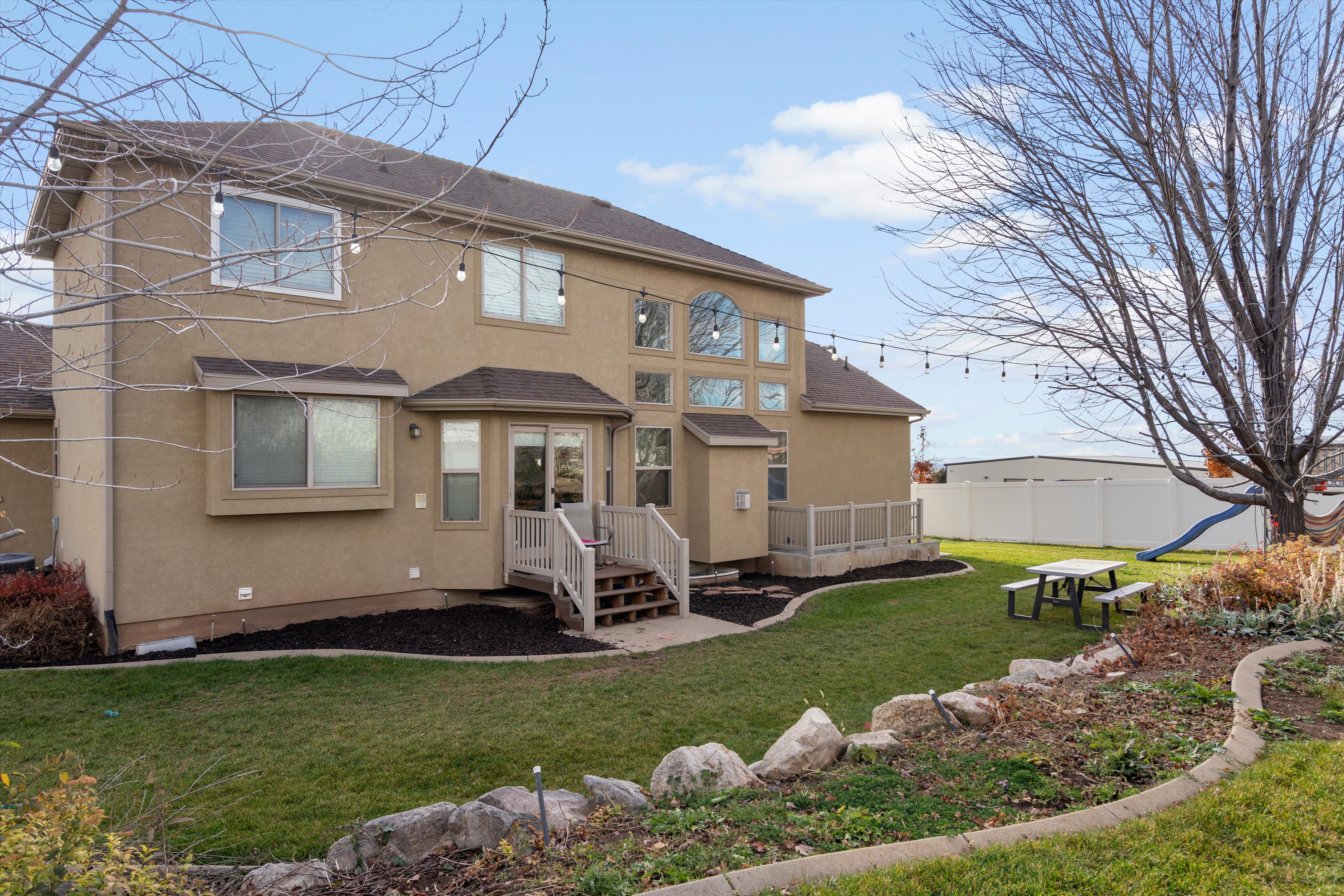 Back of property with a shingled roof and stucco siding