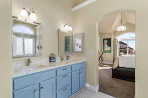 Ensuite bathroom with double vanity, light colored carpet, and healthy amount of natural light