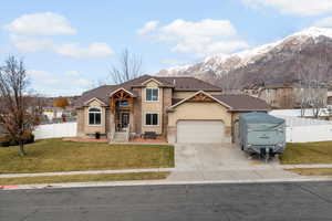 View of front of property with stucco siding, a garage, driveway, a mountain view, and a residential view