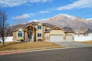 View of front facade with stucco siding, a garage, driveway, and a mountain view