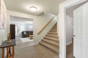 Stairs with carpet flooring and a textured ceiling