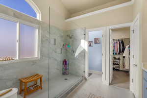 Bathroom featuring walk in shower, vanity, light marble finish floors, and a spacious closet