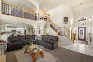 Living room with arched walkways, a chandelier, carpet flooring, and a high ceiling
