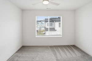 Spare room featuring light colored carpet and a ceiling fan