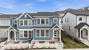 View of front of house featuring board and batten siding, roof with shingles, a fenced front yard, and a mountain view