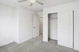 Unfurnished bedroom with light colored carpet, a closet, and ceiling fan