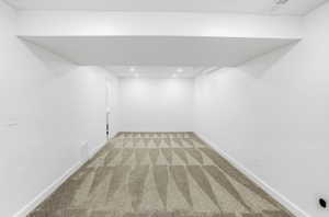 Finished basement with light colored carpet and recessed lighting