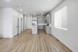 Kitchen featuring gray cabinets, a kitchen island with sink, stainless steel appliances, light wood-type flooring, and recessed lighting