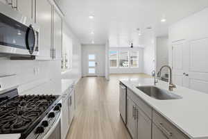 Two tone kitchen featuring stainless steel appliances, light wood-style flooring, light stone counters, a textured ceiling, and recessed lighting