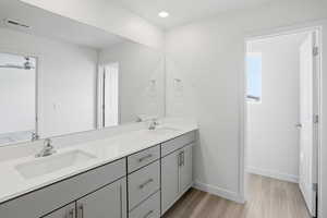 Bathroom with double vanity, light wood finished floors, and recessed lighting