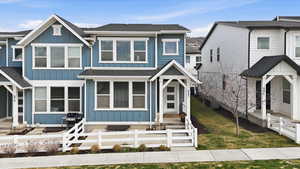 View of front facade with board and batten siding, a fenced front yard, and a shingled roof
