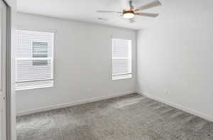 Empty room with light colored carpet and ceiling fan