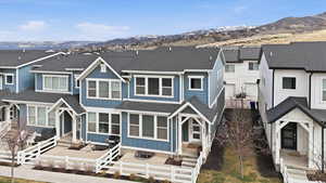 View of front of house with a shingled roof, board and batten siding, a fenced front yard, and a mountain view