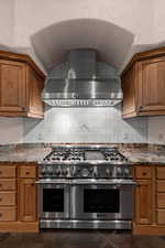 Kitchen with double oven range, wood finish cabinets, and light stone counters