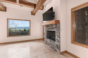 Unfurnished living room featuring a fireplace, beamed ceiling, and light tile patterned flooring