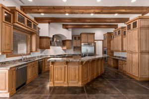Kitchen featuring glass insert cabinets, tasteful backsplash, dark stone counters, beam ceiling, and stainless steel appliances