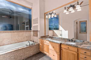Primary full bath with a ceiling fan, double vanity, and a bath