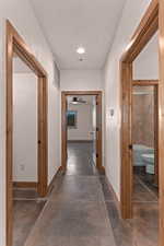 Corridor with a textured wall, concrete flooring, and recessed lighting