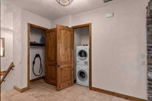 Garage mudroom/foyer with laundry area with stacked washer / dryer and light tile patterned floors