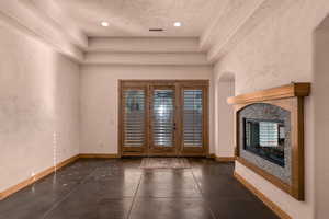 Formal dining room featuring a multi sided fireplace, french doors, a raised ceiling, and recessed lighting