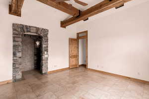 Unfurnished living room featuring a ceiling fan and beamed ceiling