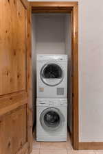 Mudroom has a stacked laundry behind door with light tile patterned floors and stacked washer / dryer