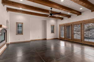 Unfurnished living room with beamed ceiling, ceiling fan, recessed lighting, and a glass covered fireplace