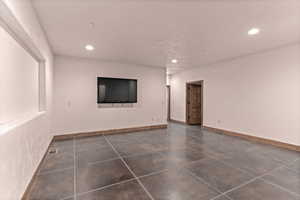 Empty great room featuring dark cement patterned flooring and recessed lighting